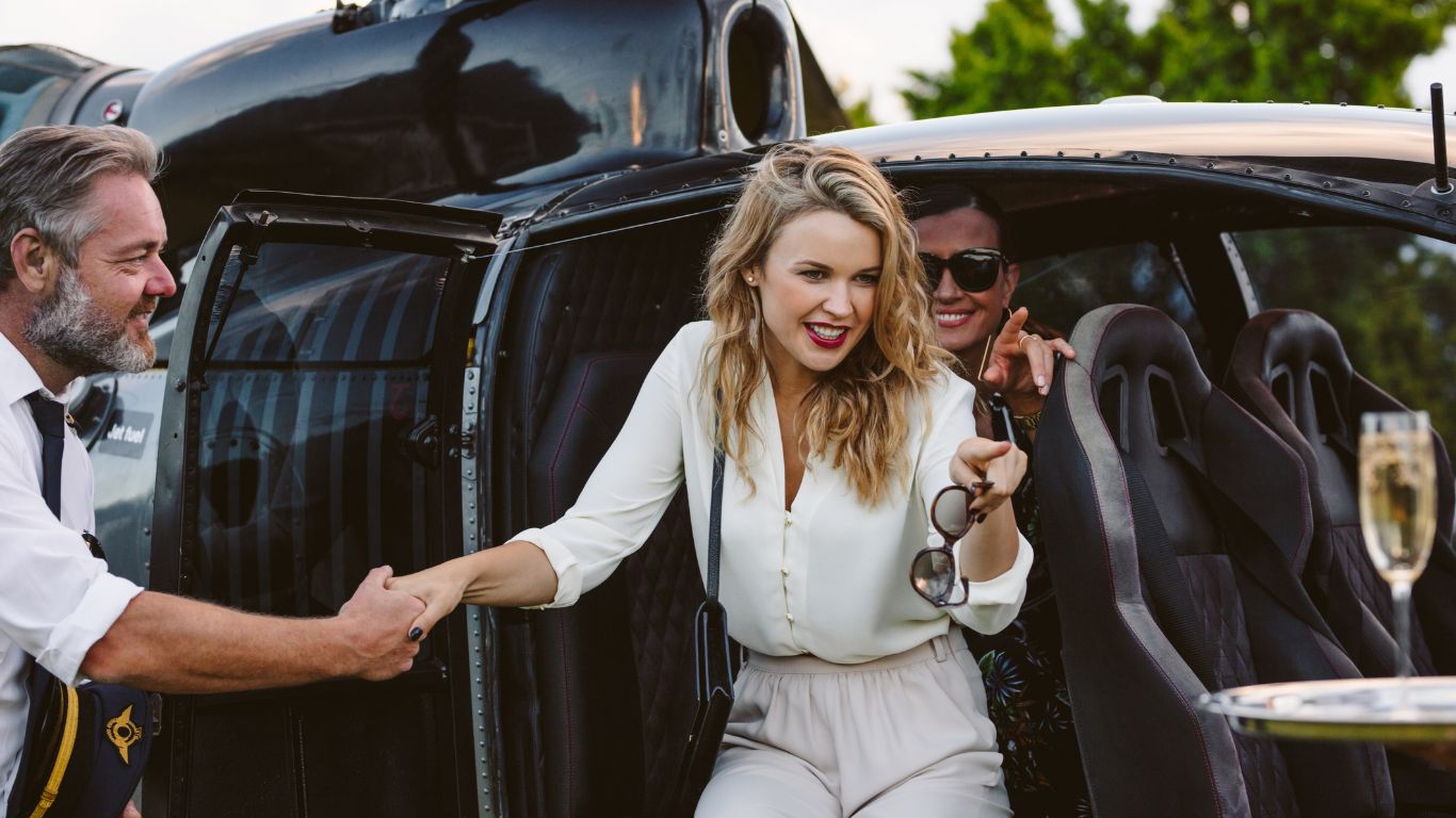 Deux femmes élégantes sortant d'un hélicoptère, accueillies avec soin par un pilote professionnel, illustrant les services de transport exclusifs proposés par Azur Dream Saint-Tropez