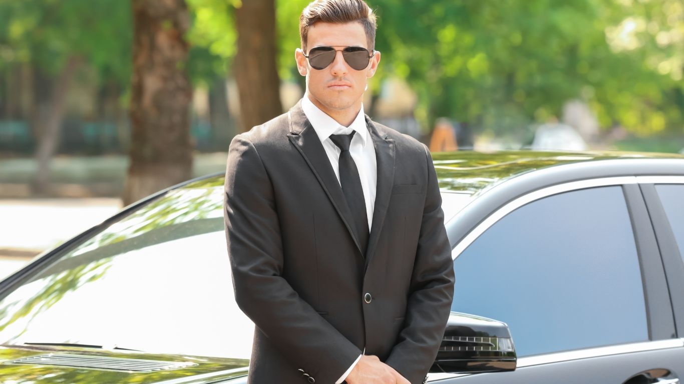 Professional security agent in an elegant suit beside a luxury car, Azur Dream close protection in Saint-Tropez