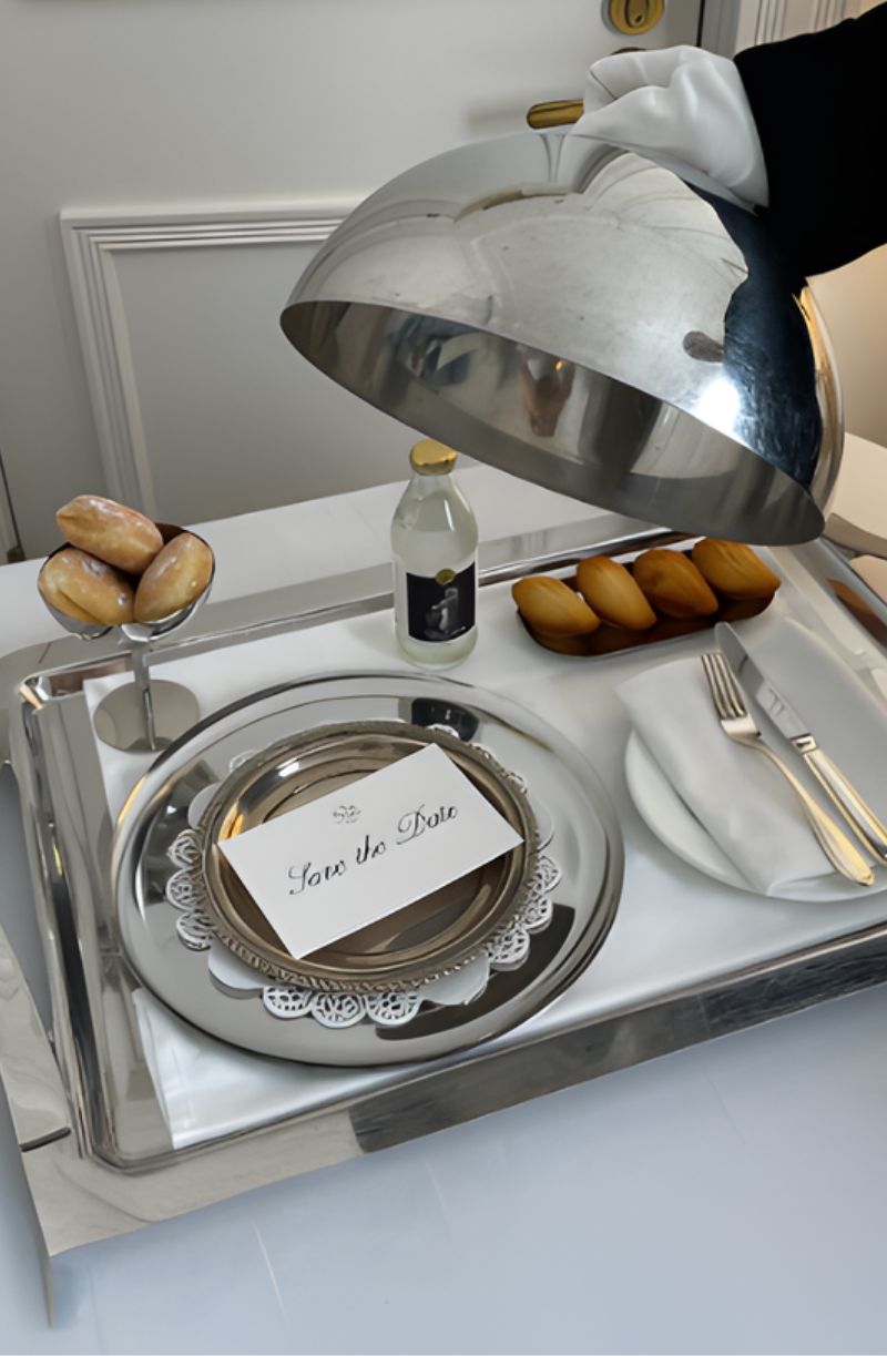 Cloche élégante soulevée révélant un message “Save the Date” pour un événement privé.