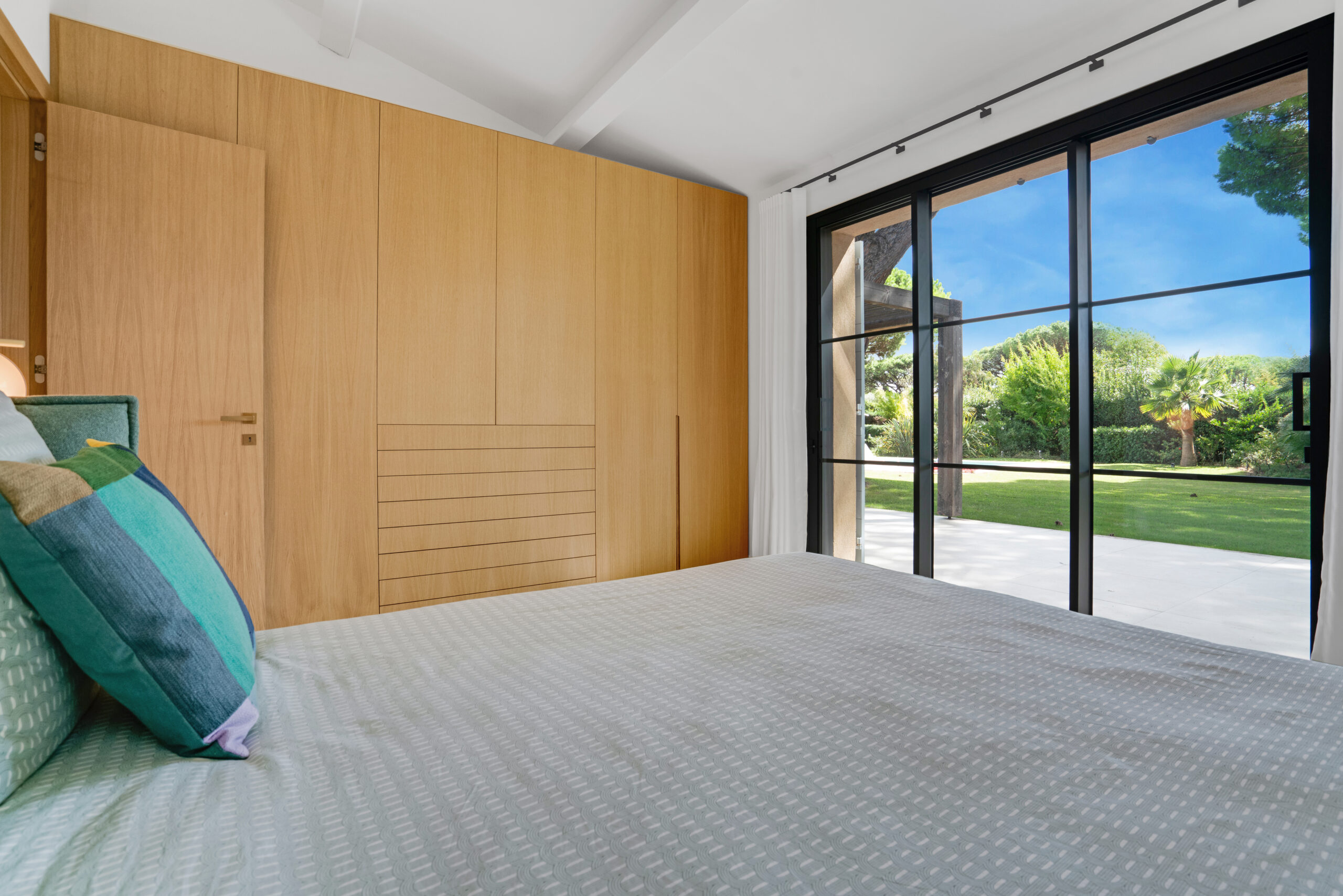 Bedroom with light wood panelling and picture window at Villa Charlotte