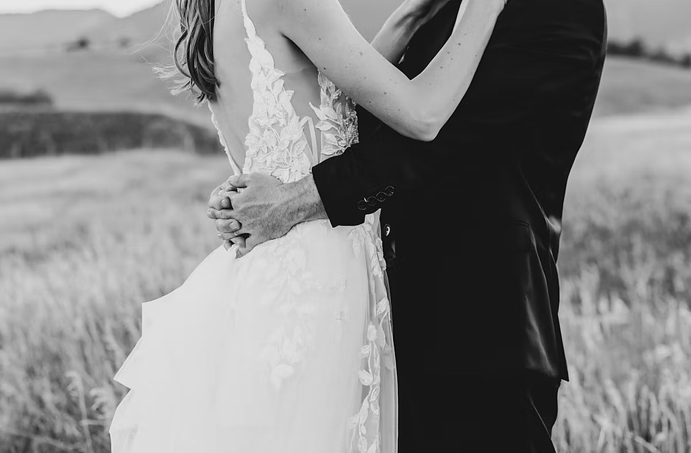 The newlyweds embracing in tall grass, backless lace gown, black and white portrait, wedding in Provence