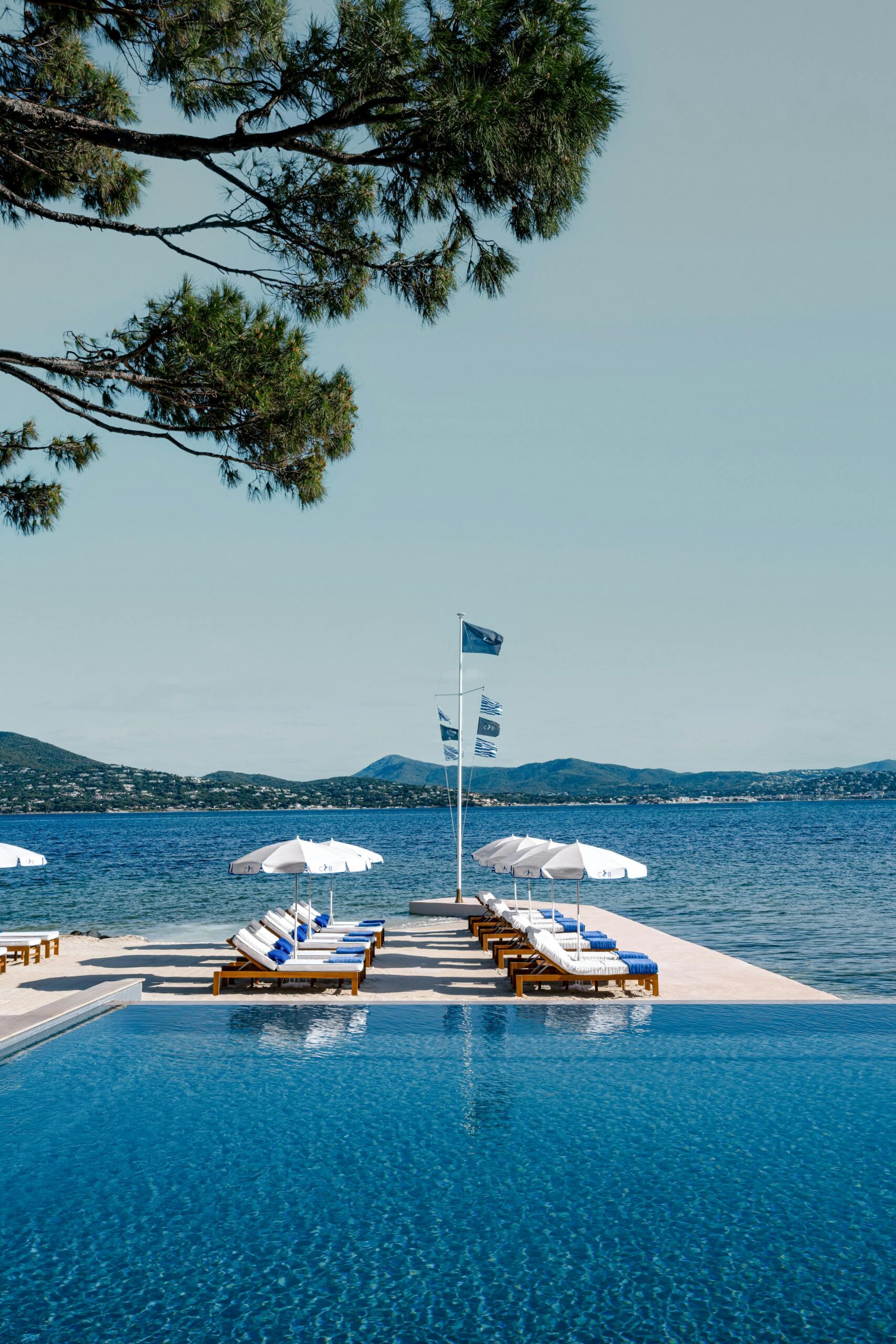La plage privée du Cheval Blanc St-Tropez, parasols blancs face à la baie des Canebiers