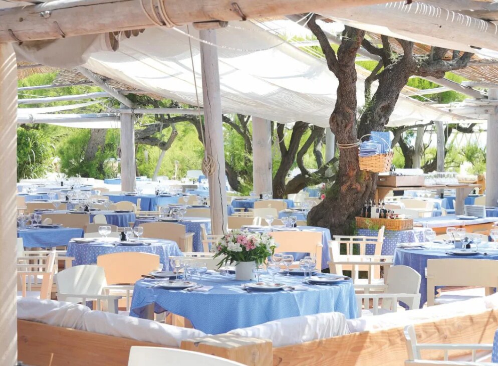 Les tables aux nappes bleues du restaurant du Club 55, sous les tamaris de Pampelonne à Ramatuelle