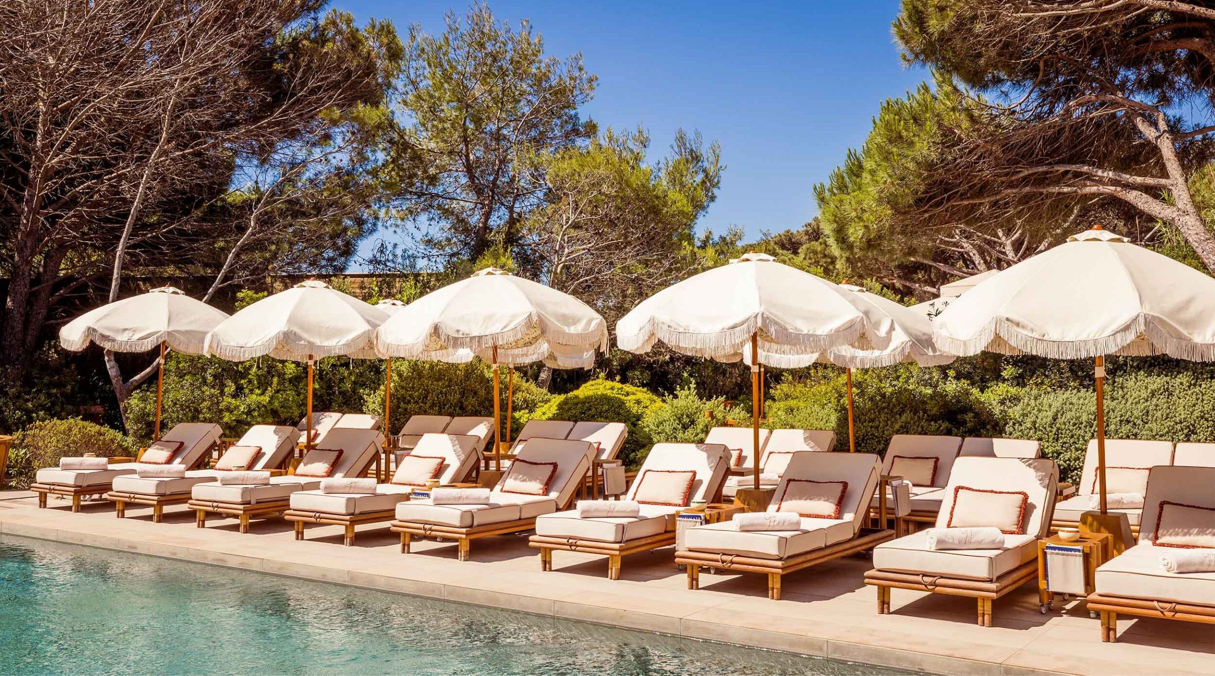 Transats et parasols blancs autour de la piscine de Gigi à Ramatuelle