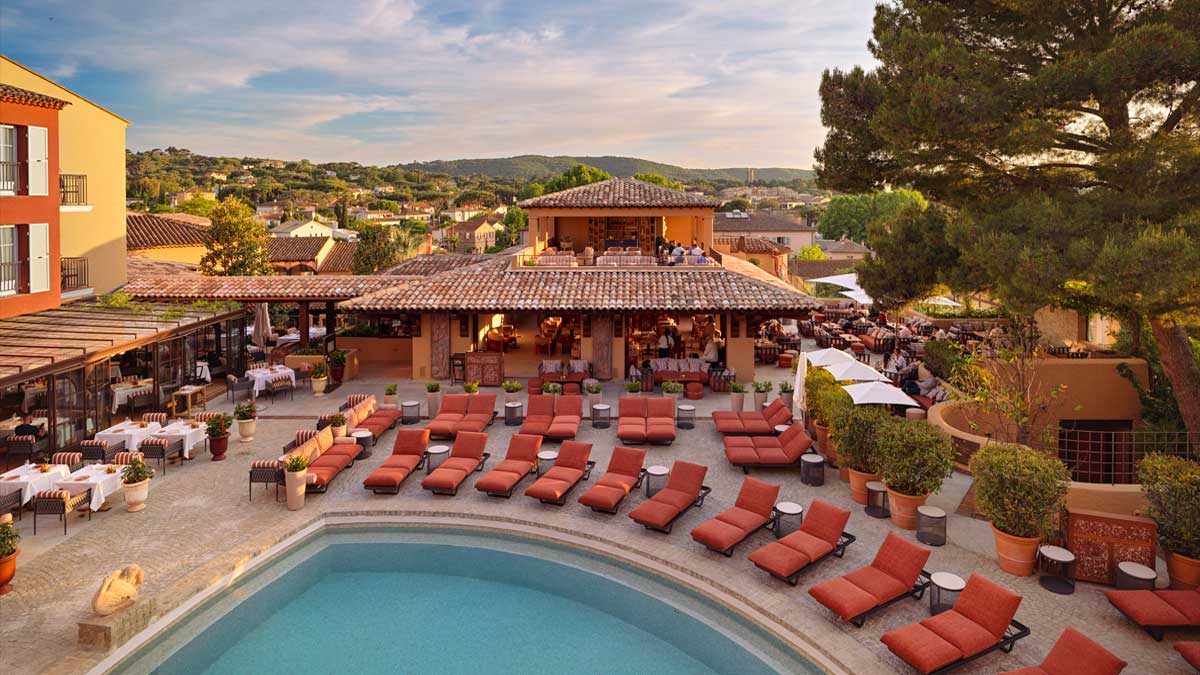 La piscine de l'Hôtel Byblos entourée de transats rouges et des façades provençales